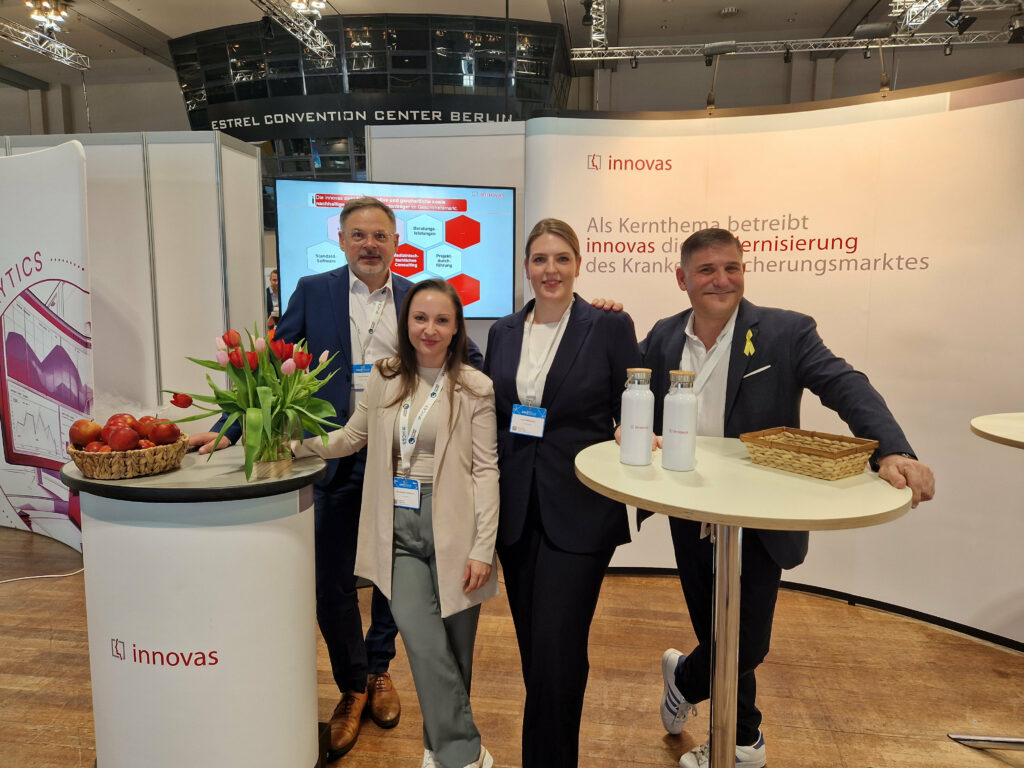 Vier innovas-Mitarbeitende stehen vor unserem Messestand