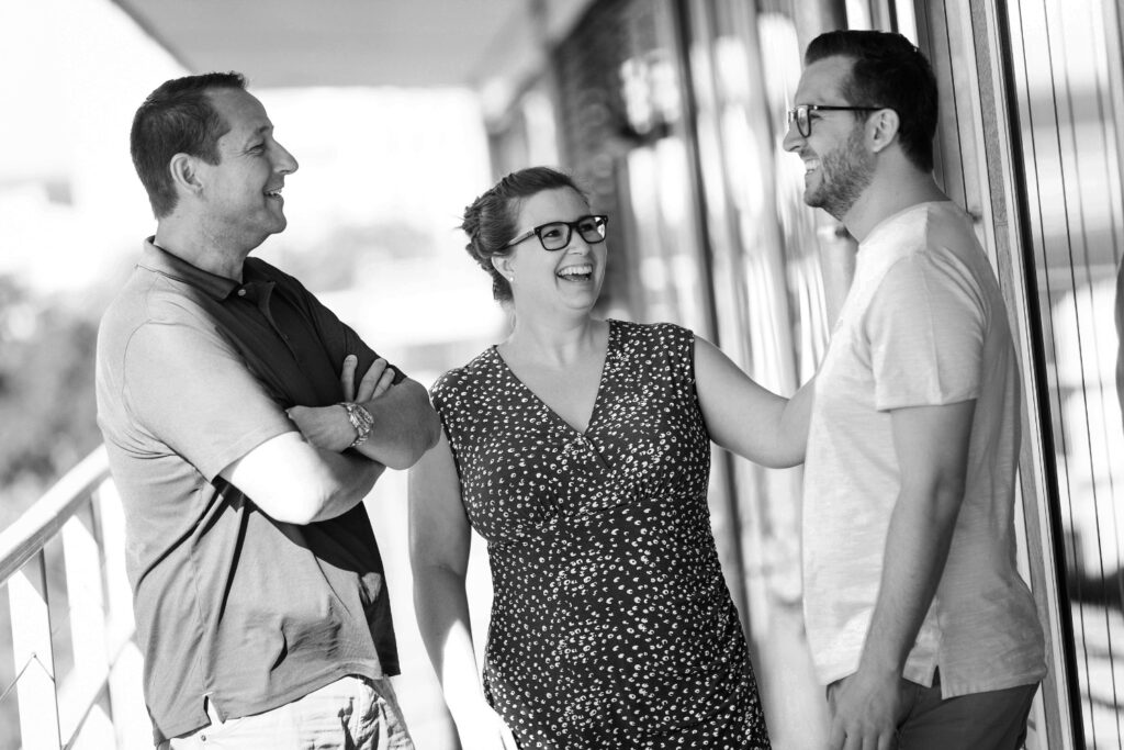 Drei innovas-Mitarbeitende stehen lachend auf der Terrasse am Theodor-Heuss-Ring